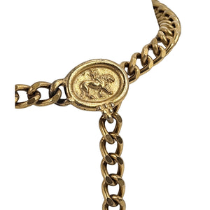 Gold coin medallion buckle detail on linked chain belt with clasp and dangling chain