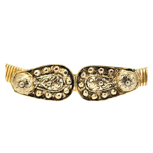 Gold-tone stretch belt close-up of ornate oval buckle with engraved floral details
