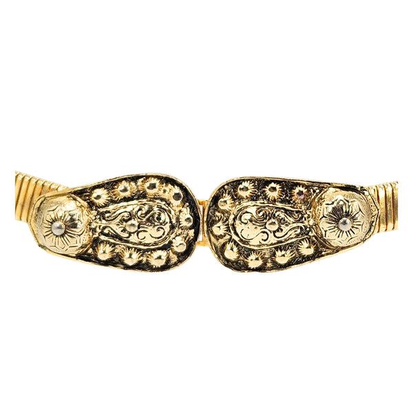 Gold-tone stretch belt close-up of ornate oval buckle with engraved floral details