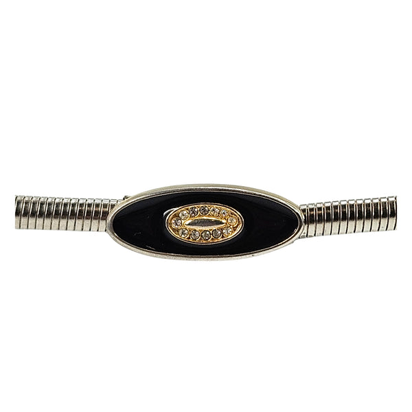 Silver-tone snake chain belt close-up: black oval buckle with gold crest centerpiece