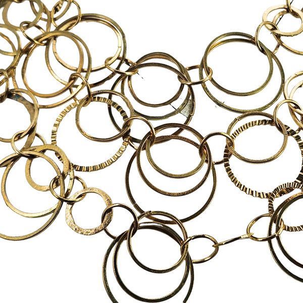 Close-up of gold ring bib necklace with layered round hoops and chain links.