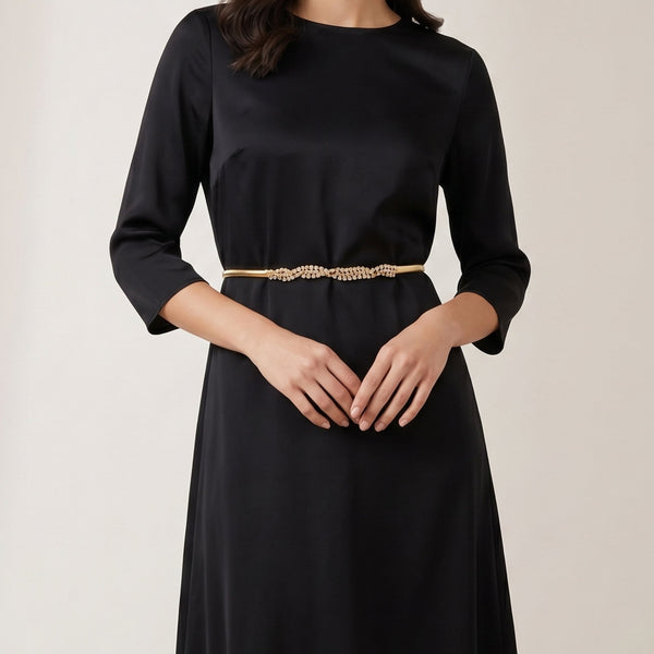 Gold-tone stretch snake belt with rhinestone center, worn at waist over black dress