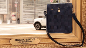 Woven navy leather crossbody bag with flap and gold lock, adjustable strap
