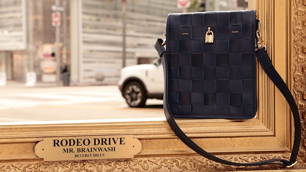 Woven navy leather crossbody bag with flap and gold lock, adjustable strap