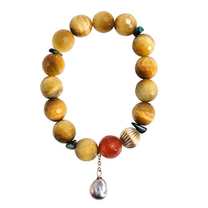 Yellow beaded stretch bracelet with red bead, metal coil, and dangling pearl charm