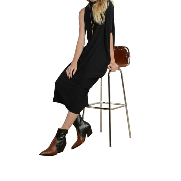 Mockneck sleeveless black midi dress with side slit, model seated