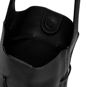 Black leather bucket bag close-up of pebble-grain texture and snap pocket