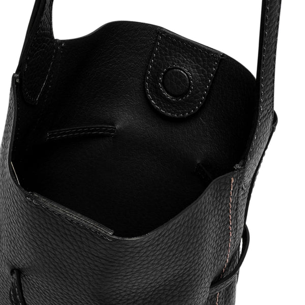 Black leather bucket bag close-up of pebble-grain texture and snap pocket