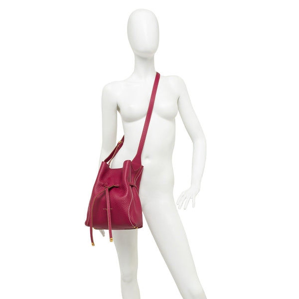 Pink leather bucket bag on model with drawstring top and shoulder strap