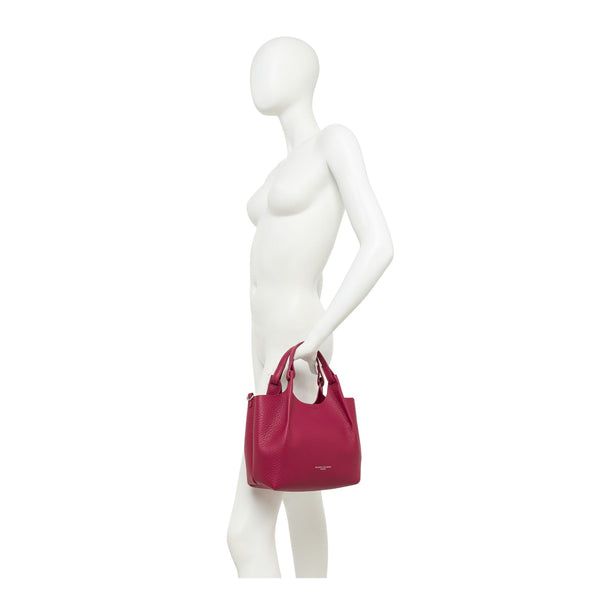 Mannequin holding a small magenta handbag with a short top handle
