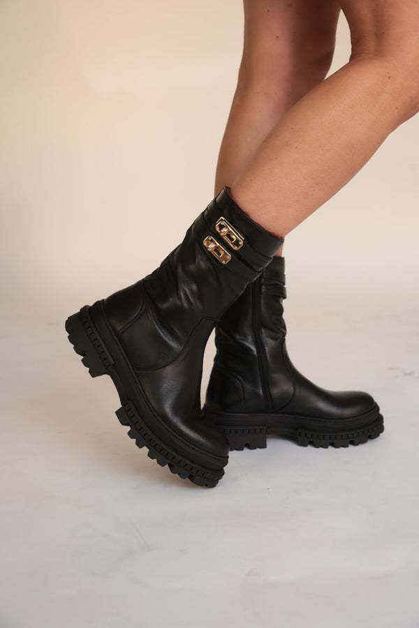 Black shearling-lined boots with buckle strap and lug sole, side view