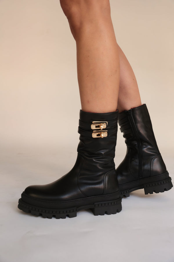 Black shearling-lined lug-sole boots with double buckle strap, front view