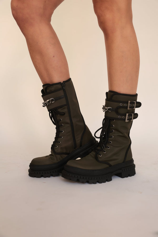 Black lace-up combat boots with buckled straps and chunky lug soles