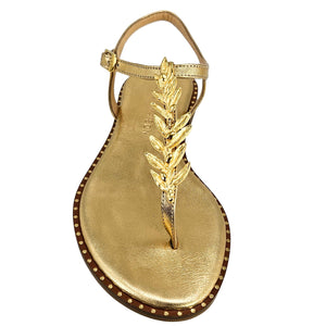 Gold leather thong sandal with tall leaf ornament and studded sole edge, flat