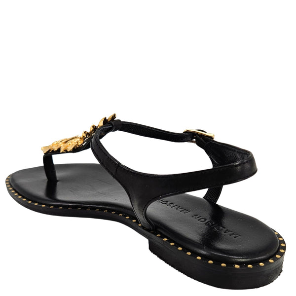 Black thong sandal angled view with gold leaf strap detail and studded outsole trim