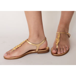 Gold leather flat thong sandal with gold leaf strap detail and tan sole