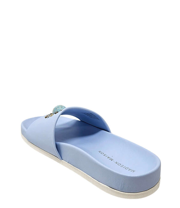 Sky blue open-toe slide sandal, side view; oval jewel on wide strap, flat sole