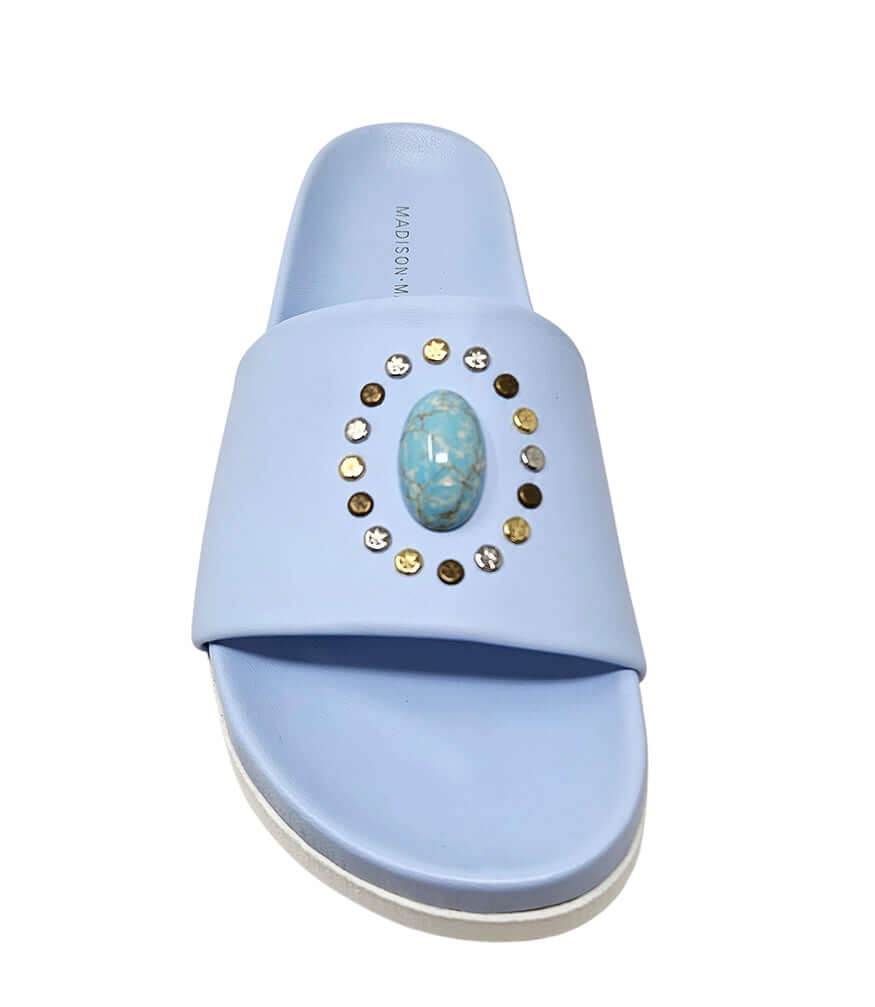 Sky blue open-toe slide sandal with oval jewel and gold stud accents, flat sole