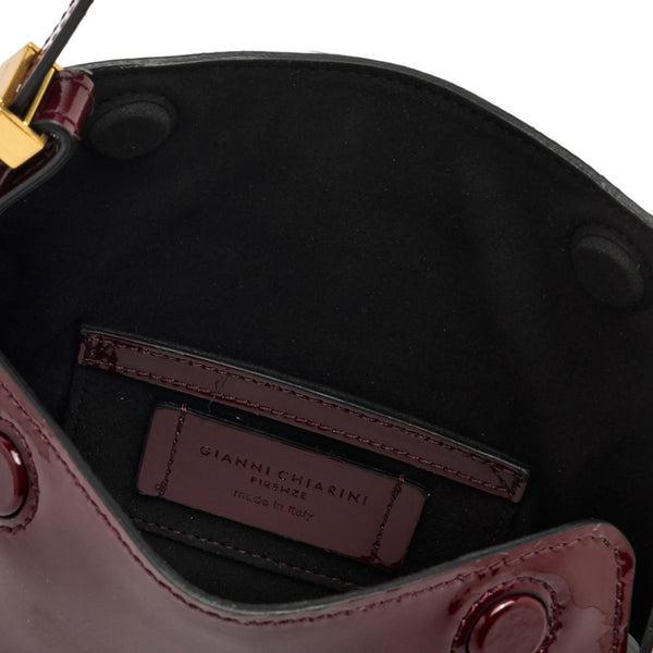 Dark berry patent-leather handbag interior with logo patch and stitched pocket